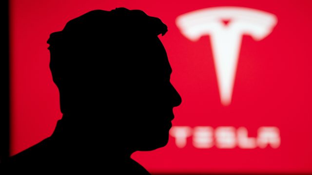 Silhouette of Elon Musk portrait, billboard of Tesla on red background — Photo by kovop58@gmail.com