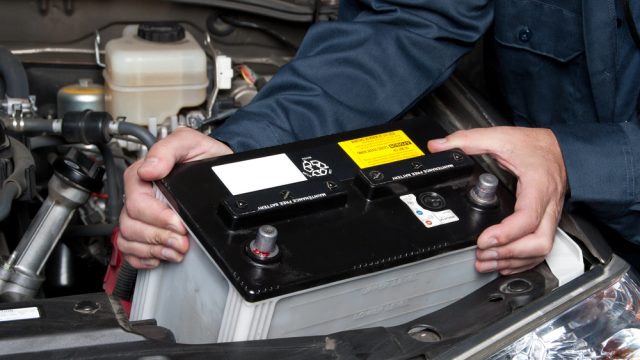 Auto mechanic replacing car battery