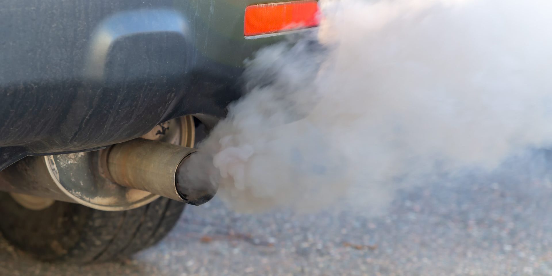 Thick smoke pours from the exhaust pile on a car. Shallow depth of field, focus on the end of the tail pipe. Closeup view.