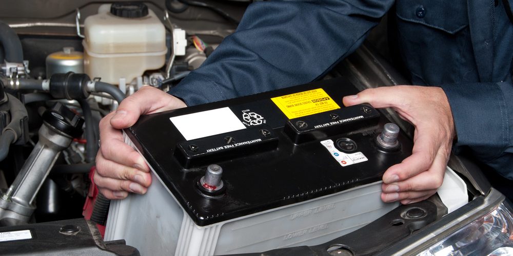 Auto mechanic replacing car battery