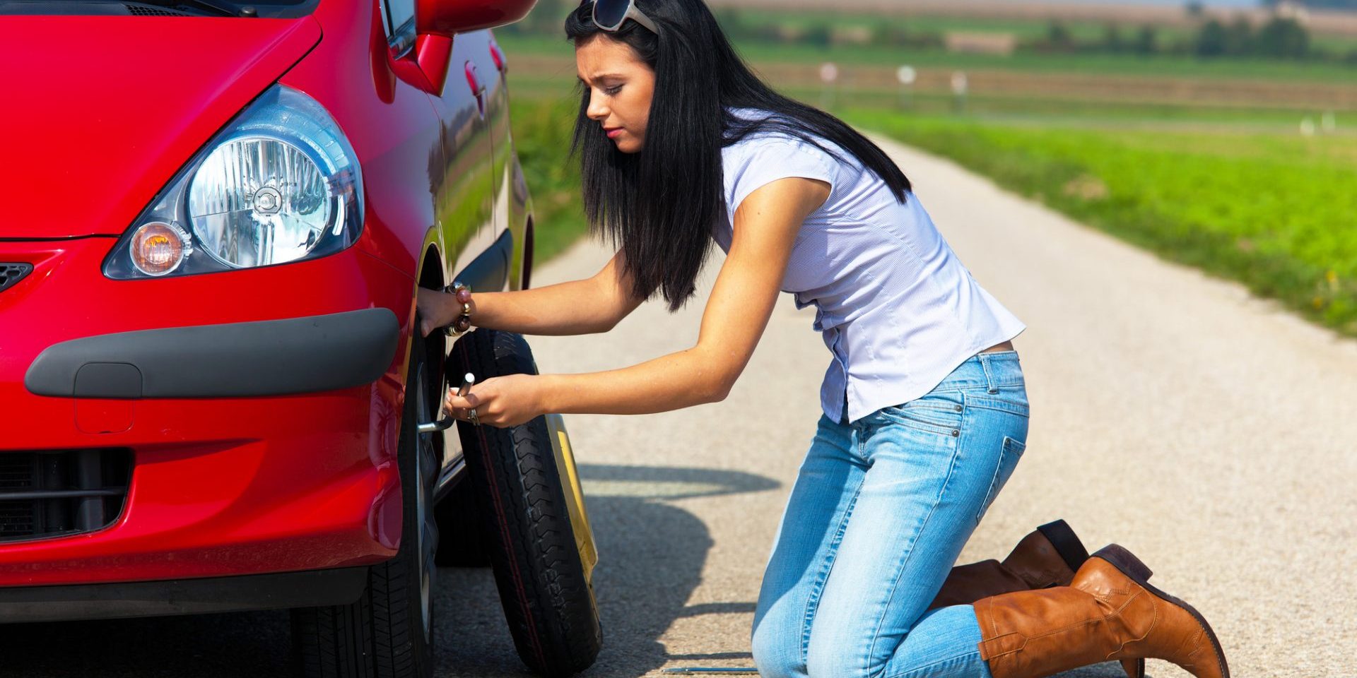 Young woman with a flat tire on car