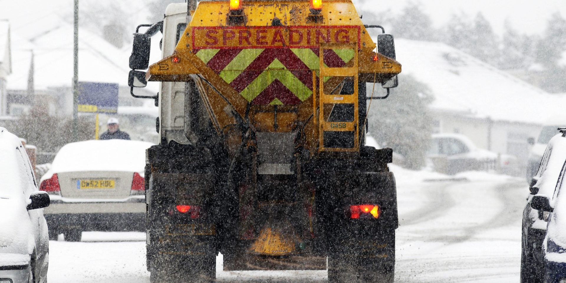 A gritter spreading salt on a road in the winter snow, South East London, UK .