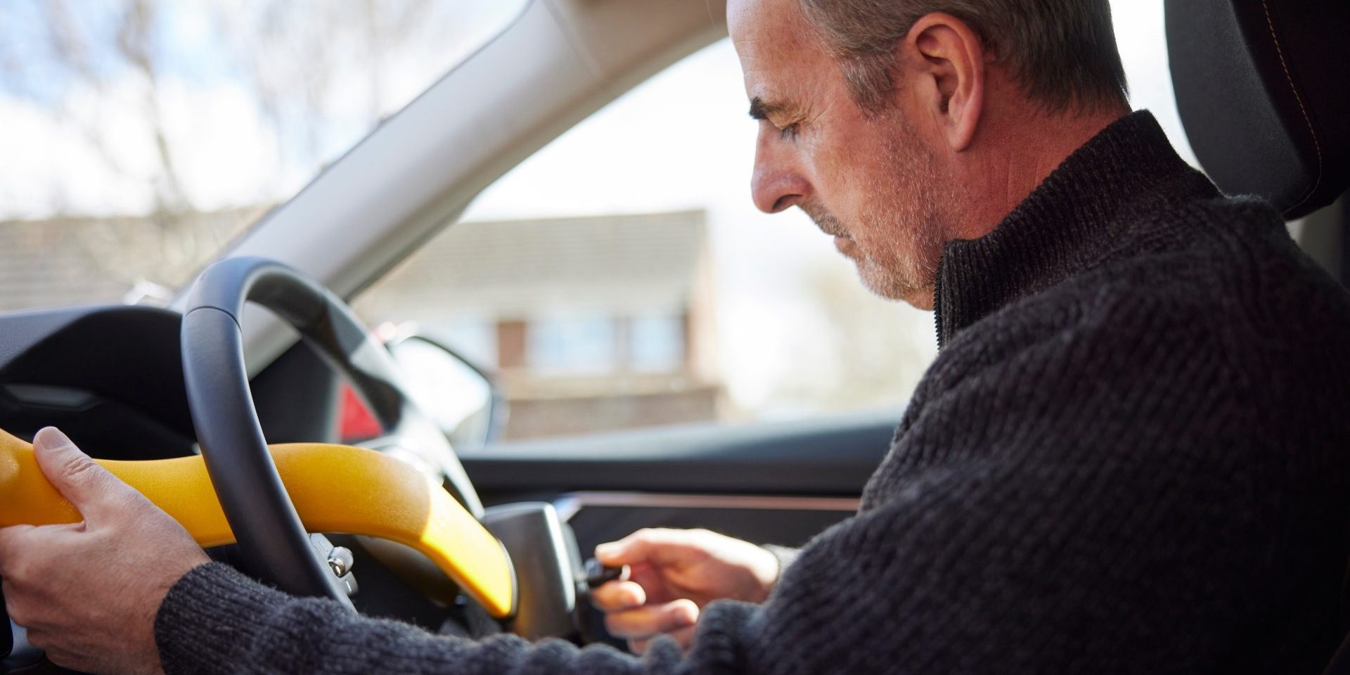 Mature Man Fitting Manual Steering Wheel Lock In Car (image courtesy eBay)